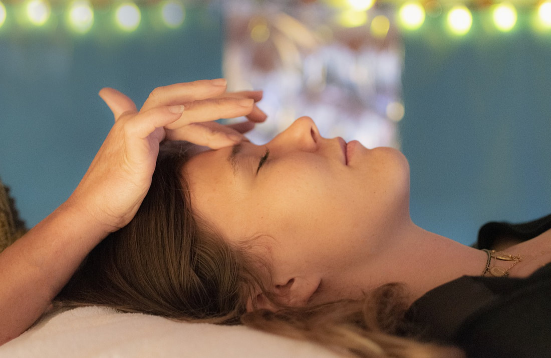 relaxed woman receiving therapeutic energy work to points on forehead